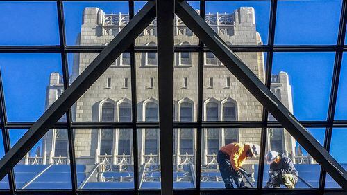 Workers straddle the beams of the skylight of the City of Atlanta’s city Hall’s atrium where maintenance work was conducted. In the background is the older city hall building. JOHN SPINK /JSPINK@AJC.COM AJC File Photo