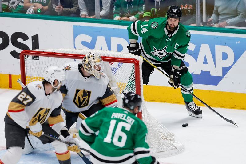 Dallas Stars' Jamie Benn (14) controls the puck as he and teammate Joe Pavelski (16) attack against Vegas Golden Knights defenseman Shea Theodore (27) and goaltender Adin Hill during the second period in Game 7 of an NHL hockey Stanley Cup first-round playoff series, Sunday, May 5, 2024, in Dallas. (AP Photo/Brandon Wade)