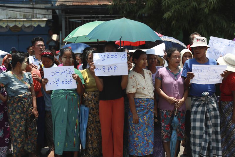 Family members and colleagues wait for prisoners to be released from Insein Prison Wednesday, April 17, 2024, in Yangon, Myanmar. On Wednesday Myanmar's military government granted amnesty for over 3,000 prisoners to mark this week’s traditional New Year holiday. The signs show their family name. (AP Photo/Thein Zaw)