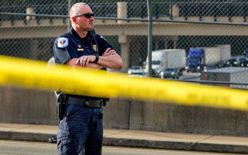 A Cobb County police officer stands at the scene of an officer-involved shooting on Chastain Road at the I-75 overpass. 
