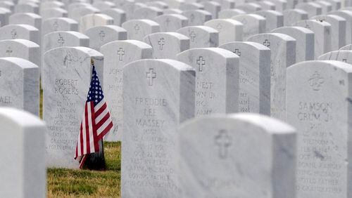 this May 22, 2020 photo, a U.S. flag decorates a veteran's grave at Alabama National Cemetery in Montevallo, Ala. Because of the coronavirus pandemic, the government has banned public ceremonies and the mass placement of flags on graves at the country's 142 national cemeteries. With almost 4.9 million people interred in the cemeteries, thousands would attend memorial events and help mark graves with flags during a typical Memorial Day weekend. (AP Photo/Jay Reeves)