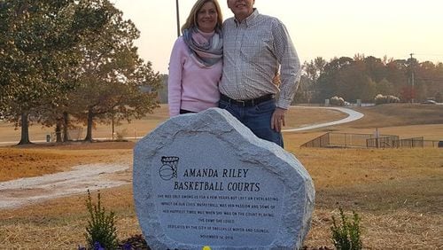 Amanda Riley’s parents, Barbara and Steve Riley, shown here with the marker designating the naming of basketball courts at Briscoe Park in Snellville in honor of their daughter. Courtesy of Barbara Riley