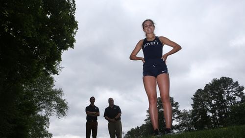Serena Tripodi (right) poses for a portrait with her coaches Jimmy Jewell (center) and Chris Mayer (left) in the background at The Lovett School in Atlanta, Georgia, on May 4, 2017. Tripodi holds seven state titles in track and cross country, with five of those being individual. (HENRY TAYLOR / HENRY.TAYLOR@AJC.COM)
