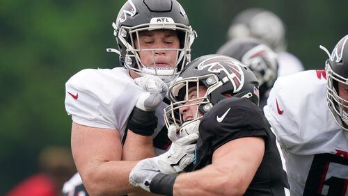 Falcons offensive guard Ryan Neuzil (left) runs drills with defensive tackle John Cominsky (center) during practice on Tuesday, Aug. 3, 2021, in Flowery Branch. (Brynn Anderson/AP)