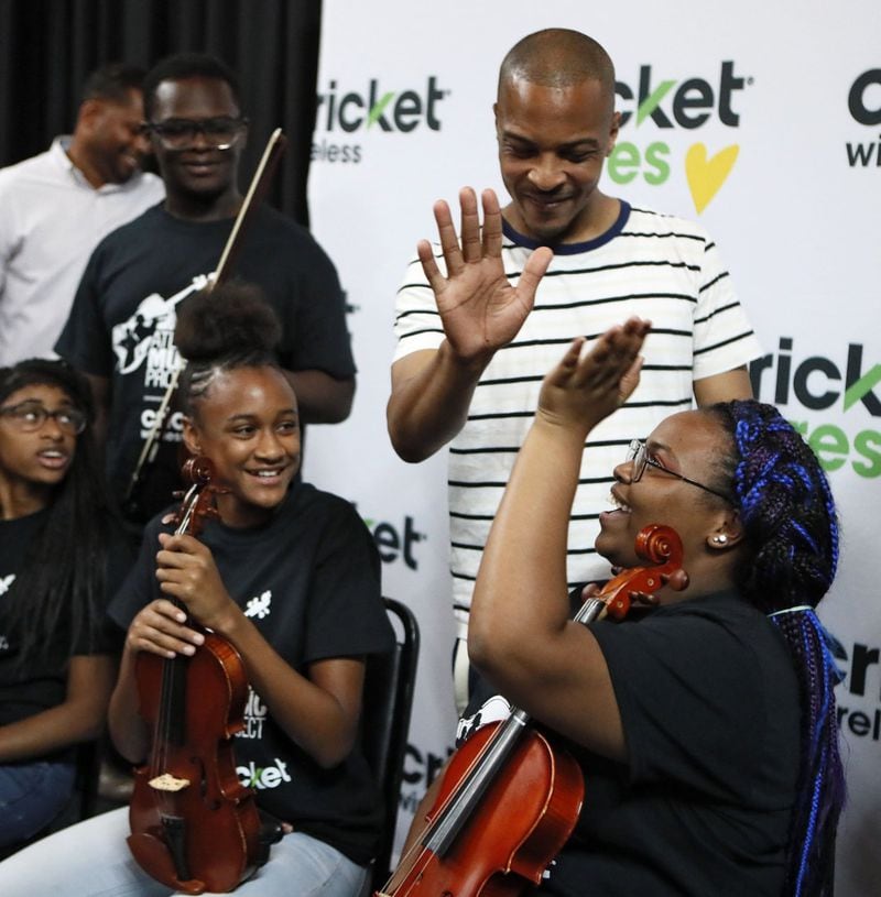 Nyasjah Brooks (right), from Carver Early College in Atlanta, gets a high-five from T.I. as he takes a break for some photos with the students who will perform with him at a July 12 event in Washington, D.C. BOB ANDRES / BANDRES@AJC.COM