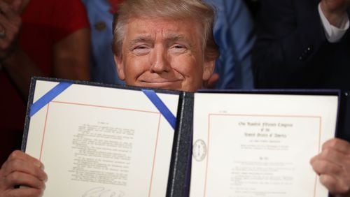 President Donald Trump holds up the Department of Veterans Affairs Accountability and Whistleblower Protection Act of 2017 after signing it Friday during a ceremony in the East Room of the White House. (Photo by Chip Somodevilla/Getty Images)