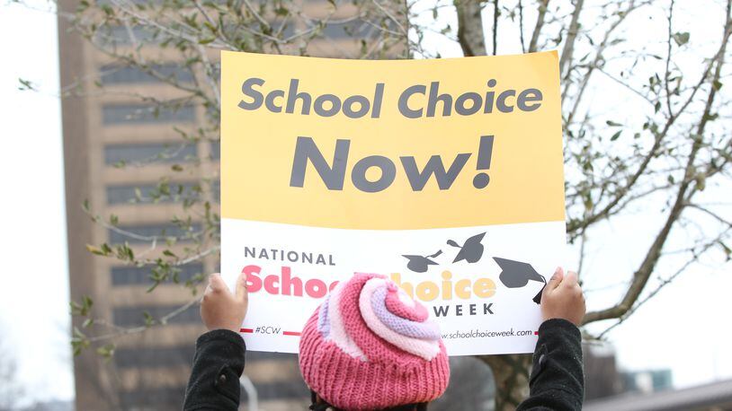 A school choice supporter holds a sign at a rally at the state Capitol. TAYLOR.CARPENTER@AJC.com