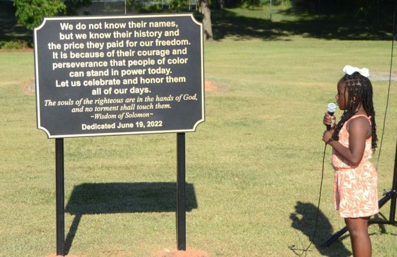 Kalaney Miller, 9, reads the inscription on the plaque dedicated to more than 100 historical Black residents buried in unmarked graves in Section 10 of the Jackson City Cemetery. (Courtesy of Larry Standford)