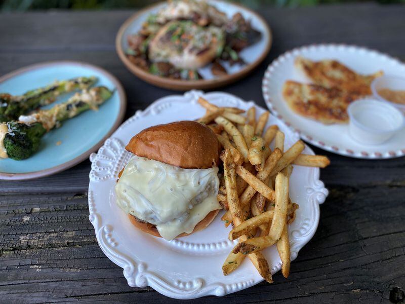 Takeout from Woodward & Park: Grilled broccoli, smoked chicken (in background), pierogis and the house burger with fries.
Wendell Brock for The Atlanta Journal-Constitution