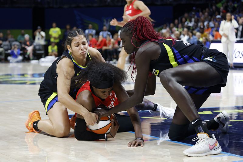 Dallas Wings guard Veronica Burton, left, and center Awak Kuier, right, vie against Atlanta Dream guard Rhyne Howard, center, for the ball during the first half of an WNBA basketball first-round playoff game in Arlington, Texas, Friday, Sept. 15, 2023. (Michael Ainsworth/The Dallas Morning News via AP)