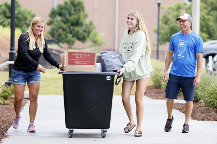 Madison Fadely  (center) pushes a cart full of her stuff with her mom Joanne Fadely while her dad Jason Fadely watches; they walk into the new building at Kennesaw State University campus. The Summit will house the 500 first-year students. (Miguel Martinez / miguel.martinezjimenez@ajc.com)