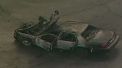 A charred Cobb County police car was cleared from the roadway after a crash in Fulton County Tuesday. The officer who was driving was seriously injured. (Credit: Channel 2 Action News)