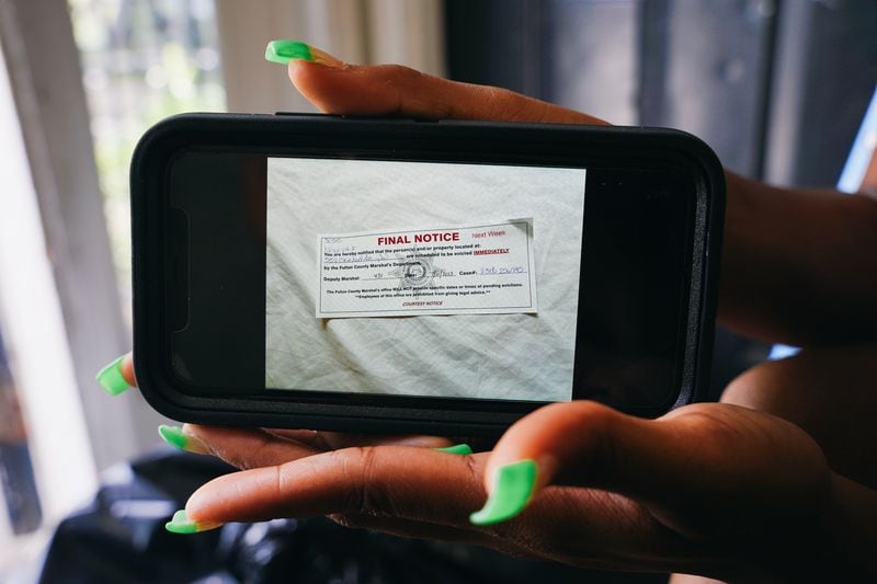 Roneisha Alford in July displays a photo she took of an eviction notice she and her mother, Constance Alford, received over unpaid rent at their Pavilion Place apartment. They said they battled problems with mold, leaks and rats in their unit for years. (Olivia Bowdoin for The Atlanta Journal-Constitution)