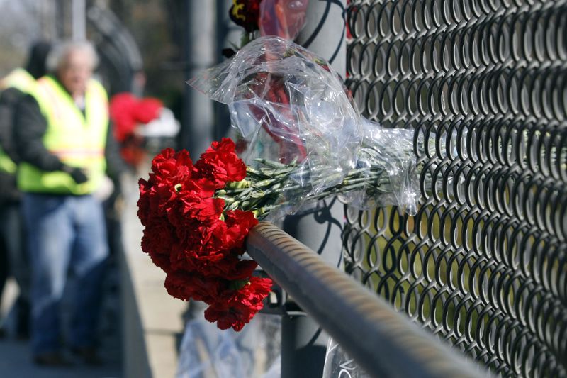 Atlanta, GA -- Flowers marked the site of the Bluffton University bus crash in Atlanta, as workers removed damaged posts and replace the fence at the scene of the bus accident on the Northside Drive overpass at I-75 south. March 4, 2007 photo. (Mikki K. Harris/ AJC staff)