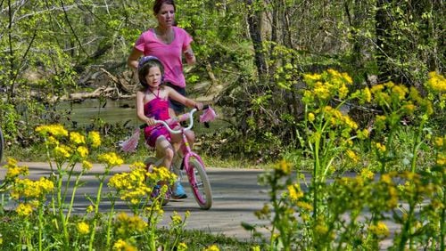 Grace Lochman (front) rides her bike as her mother, Nancy, runs next to her on the Big Creek Greenway in Alpharetta, on the Fulton County portion of the trail. JONATHAN PHILLIPS / SPECIAL