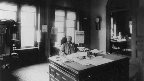 Henry A. Rucker, internal revenue collector,  seated at large desk in an Atlanta office.