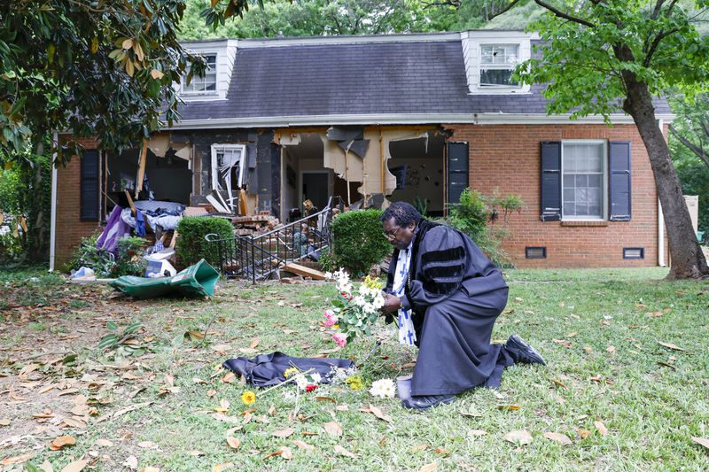 Rev. Raymond Johnson, of Marion, S.C., arranges flowers on the lawn of the home on Galway Drive in Charlotte, N.C., Tuesday, April 30, 2024 where a shootout between a suspect and officers occurred during an attempt to serve a warrant on April 29, 2024. (AP Photo/Nell Redmond)