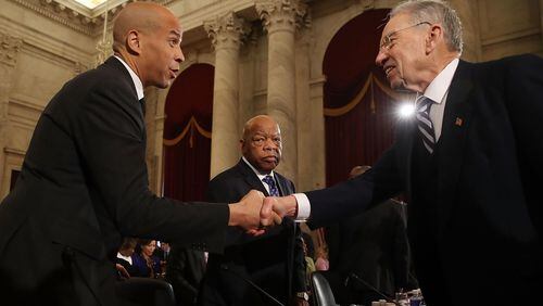 Senate Judiciary Chairman Chuck Grassley (R-IA) (R) shakes hands with Sen. Cory Booker (D-NJ) (L), as Rep. John Lewis (D-GA) stands nearby, during a confirmation hearing for Attorney General nominee Jeff Sessions (R-AL), on Capitol Hill, January 11, 2017 in Washington, DC. (Photo by Mark Wilson/Getty Images)