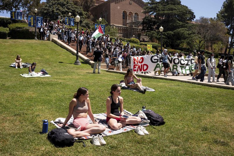 Pro-Palestinian supporters march on campus at UCLA, Monday, April 29, 2024, in Los Angeles, as other students watch from a lawn. (David Crane/The Orange County Register via AP)