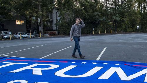 Bruno Cua unfurls a large "Trump 2020" flag during a rally in the parking lot at the Georgia Republican Party headquarters in Buckhead on Nov. 5. The FBI says the 18-year-old has been charged in connection with the Jan. 6 riot at the U.S. Capitol.