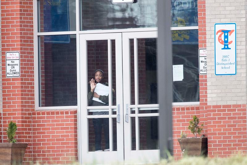 March 9, 2020, East Point:  A student waits at the front entrance at Woodland Middle School. The Fulton County School system decided the next day to close schools after a teacher tested positive with the coronavirus. The teacher was at school before testing positive. (ALYSSA POINTER/ALYSSA.POINTER@AJC.COM)