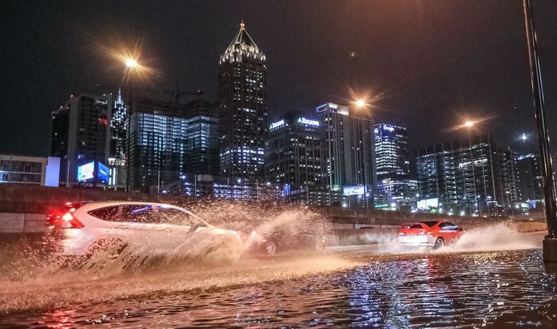 A car splashes through standing water along Techwood Drive just north of 14th Street in Atlanta on Monday morning.