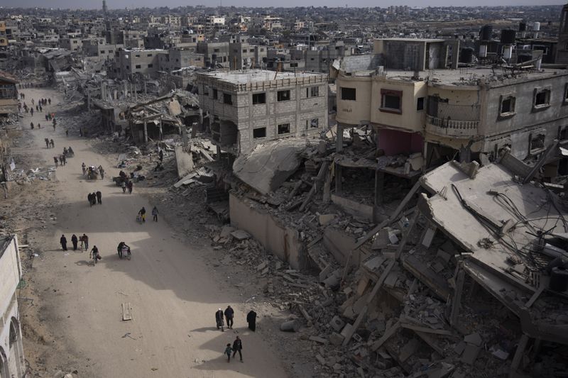 Palestinians walk through the destruction in the wake of an Israeli air and ground offensive in Khan Younis, southern Gaza Strip, Monday, April 8, 2024. Israel says it has withdrawn its last ground troops from the city, ending a four-month operation. (AP Photo/Fatima Shbair)