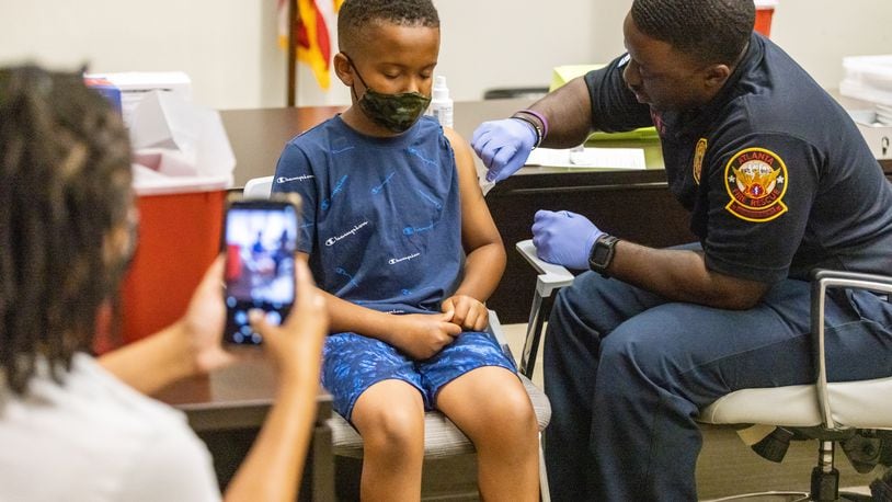 Xavier James, 11, gets ready to receive a COVID-19 shot as his mother takes his photograph during a vaccine event at Atlanta City Hall on June 25, 2022.  Steve Schaefer / steve.schaefer@ajc.com