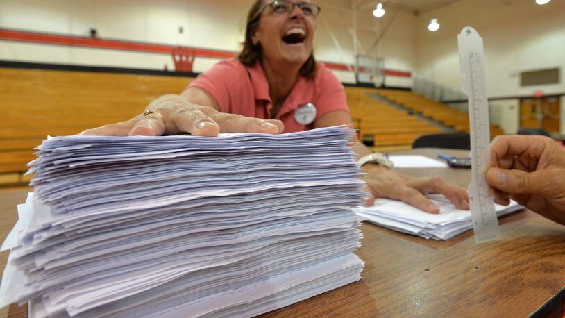 Kate Staelens reacts as she holds two stacks of "Yes" ballots on left and "No" ballots on right at Druid Hills High School on Aug. 13, 2013.