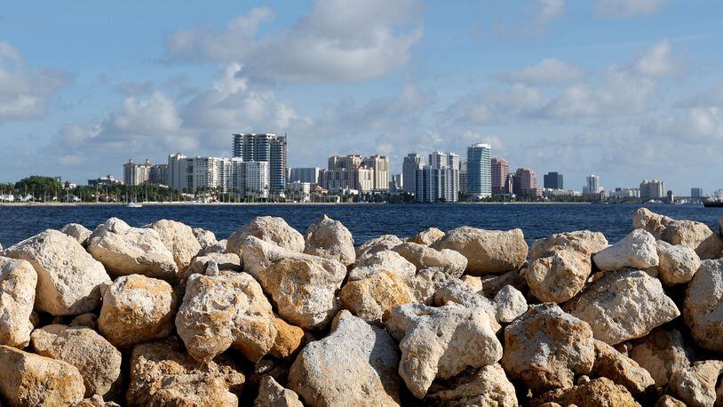 Limestone boulders meant to break up wave energy are stacked on a manmade island, part of the Palm Beach Resilient Island Project in the Tarpon Cove area near Lake Worth on July 1, 2022. Downtown West Palm Beach can be seen in the distance. The limestone will house oyster beds that naturally filter the water and abate nutrient pollution. (Amy Beth Bennett/South Florida Sun Sentinel/TNS)