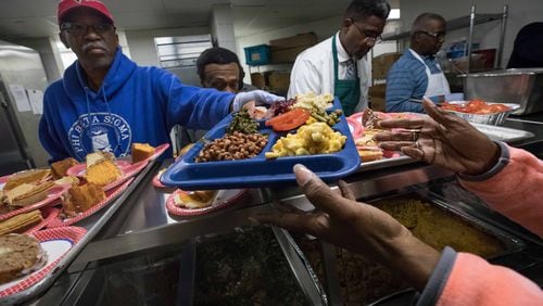 Antioch Baptist Church North Male Chorus member Al McGuire hands a Thanksgiving meal to a woman at the Salvation Army on Nov. 15, 2018, in Atlanta.  BRANDEN CAMP/SPECIAL