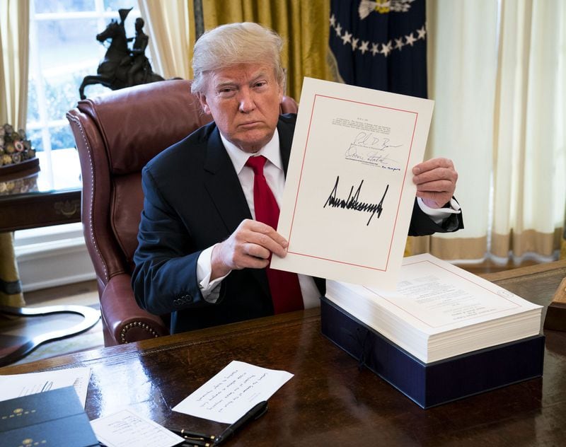 Some requirements for signatures haven’t yet disappeared. President Donald Trump displays his signature on a sweeping tax bill in the Oval Office of the White House in Washington on Dec. 22, 2017.
