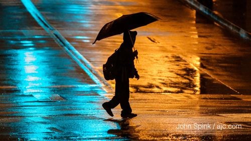 Pedestrians needed umbrellas early Tuesday on Marietta and Peachtree streets in Atlanta. JOHN SPINK / JSPINK@AJC.COM