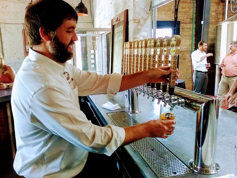 Taylor Lamm, master brewer and co-owner of Oconee Brewing Company, pours a pint in the tasting room of the new brewery in downtown Greensboro. Contributed by Blake Guthrie