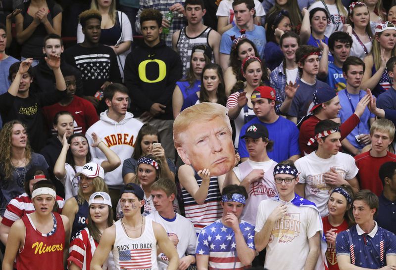In this Friday, Feb. 26, 2016 photo, the Andrean High School student section holds up a picture of GOP presidential candidate Donald Trump during their school's basketball game against Bishop Noll Institute in Merrillville, Ind. The Catholic bishop in northern Indiana denounced the students who waved the picture of Trump and shouted "build a wall" at their opponents, a heavily Hispanic school in nearby Hammond. (Jonathan Miano/The Times via AP) CHICAGO LOCALS OUT; GARY OUT; MANDATORY CREDIT