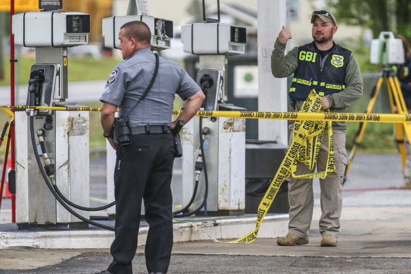 A Villa Rica police officer watches (left) as GBI agents investigate the officer-involved shooting scene at the Easy Quick Shop gas station at 1607 Bankhead Highway in Villa Rica on April 26, 2018. JOHN SPINK/JSPINK@AJC.COM