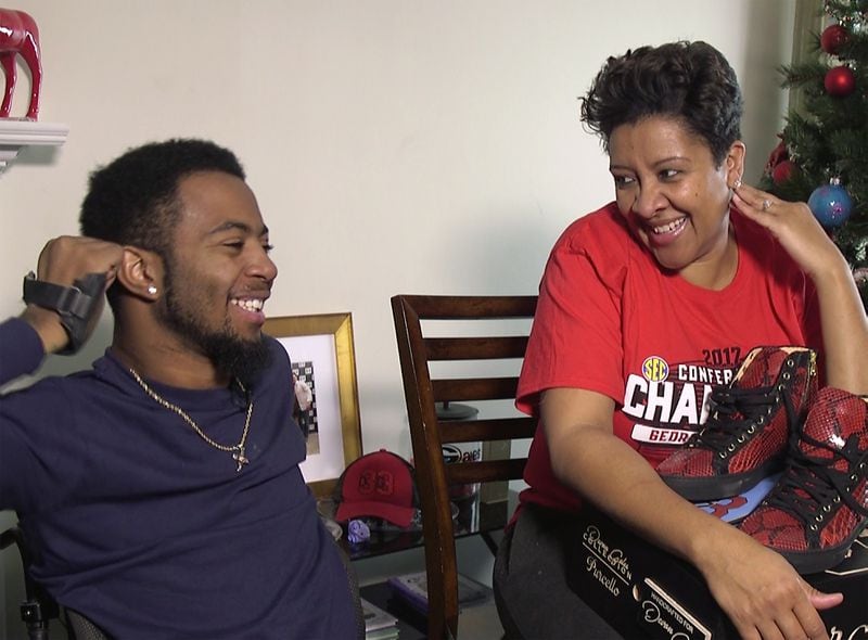 Devon Gales and mother Tish Gales share a laugh, back at their  in Lawrenceville  home after a holiday visit to Louisiana. Also pictured, the new shoes designed by Gales, done up in Georgia red and black. (RYON HORNE / RHORNE@AJC.COM)