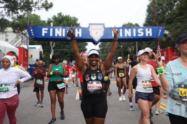 Yolanda Sterling of Snellville celebrates at the finish of the 54th running of the Atlanta Journal-Constitution Peachtree Road Race in Atlanta on Tuesday, July 4, 2023.   (Jason Getz / Jason.Getz@ajc.com)