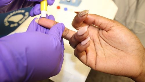 An unidentified woman gets her finger pricked for a HIV test recently in Atlanta. Contributed