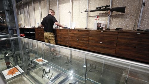 An employee cleans counters at a nearly empty display at Stoddard’s Range and Guns, in Atlanta, where the store has seen an uptick in ammunition and gun sales as the coronavirus threat intensifies. Bob Andres / robert.andres@ajc.com