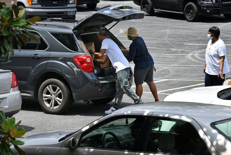 Volunteers load a car with food at the recent drive-thru food drive. (Hyosub Shin / Hyosub.Shin@ajc.com)