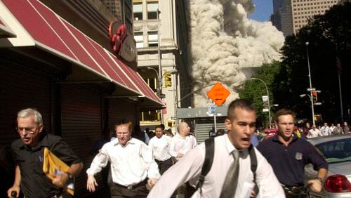 In this Sept. 11, 2001, file photo, people run from the collapse of one of the Twin Towers at the World Trade Center in New York. Stephen Cooper, far left, fleeing smoke and debris as the South Tower crumbled just a block away on Sept. 11, has died from the coronavirus, his family said, according to The Palm Beach Post.