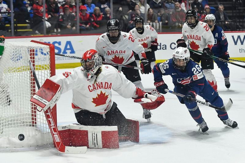 Canada goalie Ann-Renee Desbiens, left, pushes the puck wide of the goal as United States forward Kendall Coyne Schofield (26) chases during the second period in the final at the IIHF Women's World Hockey Championships in Utica, N.Y., Sunday, April 14, 2024. (AP Photo/Adrian Kraus)