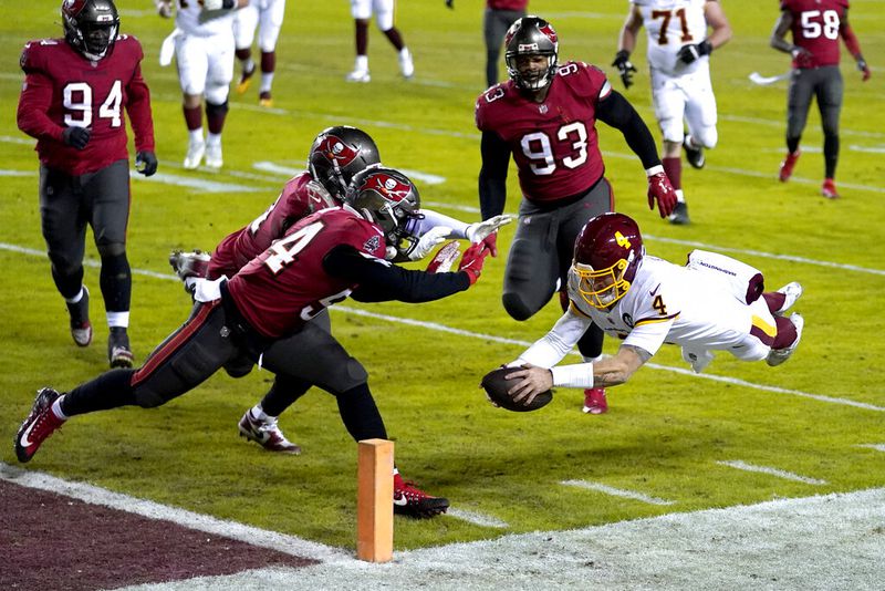 Washington Football Team quarterback Taylor Heinicke (4) dives to score a touchdown against Tampa Bay Buccaneers inside linebackers Kevin Minter (51) and Lavonte David (54) during the second half of an NFL wild-card playoff football game, Saturday, Jan. 9, 2021, in Landover, Md. (AP Photo/Julio Cortez)