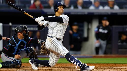 New York Yankees' Juan Soto, right, follows through on a home run against the Miami Marlins during the fourth inning of a baseball game, Monday, April 8, 2024, in New York. (AP Photo/Noah K. Murray)