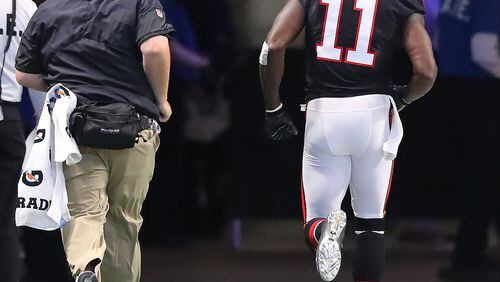 Never a good sign: Falcons wide receiver Julio Jones leaves the field in the first half Sunday for an injury inspection. He didn't return to the game. (Curtis Compton/ccompton@ajc.com)