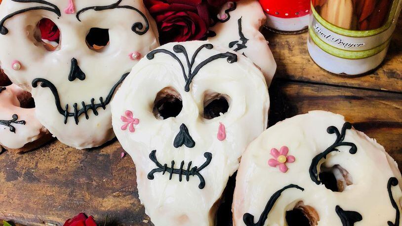 Tres Leches Sugar Skull Doughnuts from Doughnut Dollies and Chef-Owner Anna Gatti are soaked in three milks when hot, tossed in cinnamon sugar, and iced with vanilla icing and a sugar skull decoration for Dia de los Muertos. The specialty doughnut will be available from Monday, Oct. 29, through Friday, Nov. 2, at Doughnut Dollies flagship location in Marietta. CONTRIBUTED BY DOUGHNUT DOLLIES
