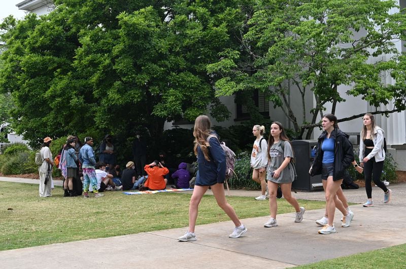 Students walk by Pro-Palestinian protesters gathering on University of Georgia campus, Tuesday, April 30, 2024, in Athens.  (Hyosub Shin / AJC)