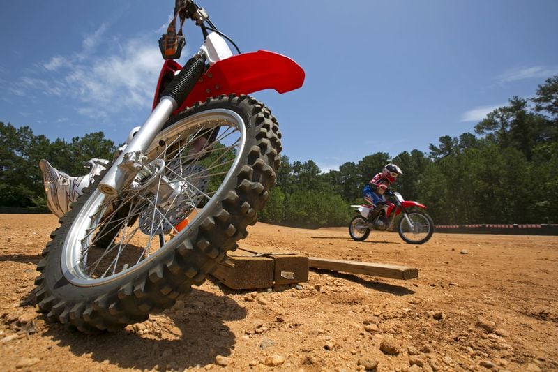 In this 2016 AJC file photo, Tavon Alston of Atlanta (right) rides a dirt bike during a kid’s basic dirt bike class at the Motorcycle Safety Foundation campus in Alpharetta. Also pictured is the dirt bike of coach Mike Penland. The campus provides classes in motorcycle safety and how to become a more skilled rider. (JASON GETZ / AJC FILE)