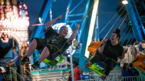 Trent Jurek, left, and Kaitlyn Concepcion ride the carnival swings during the first night of the South Florida Garlic Fest in Lake Worth on Friday, Feb. 10, 2017. Garlic Fest serves as a space for homegrown talent and a cultural showcase providing an outlet for local artists and chefs to express themselves. The festival will run until Sunday, Feb. 12, 2017. (Michael Ares / The Palm Beach Post)